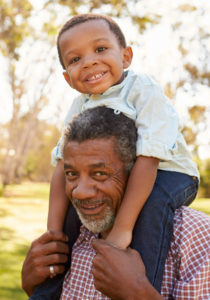 A black man is carrying a young boy on his shoulders.