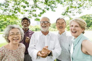 A group of older people smiling in a park.