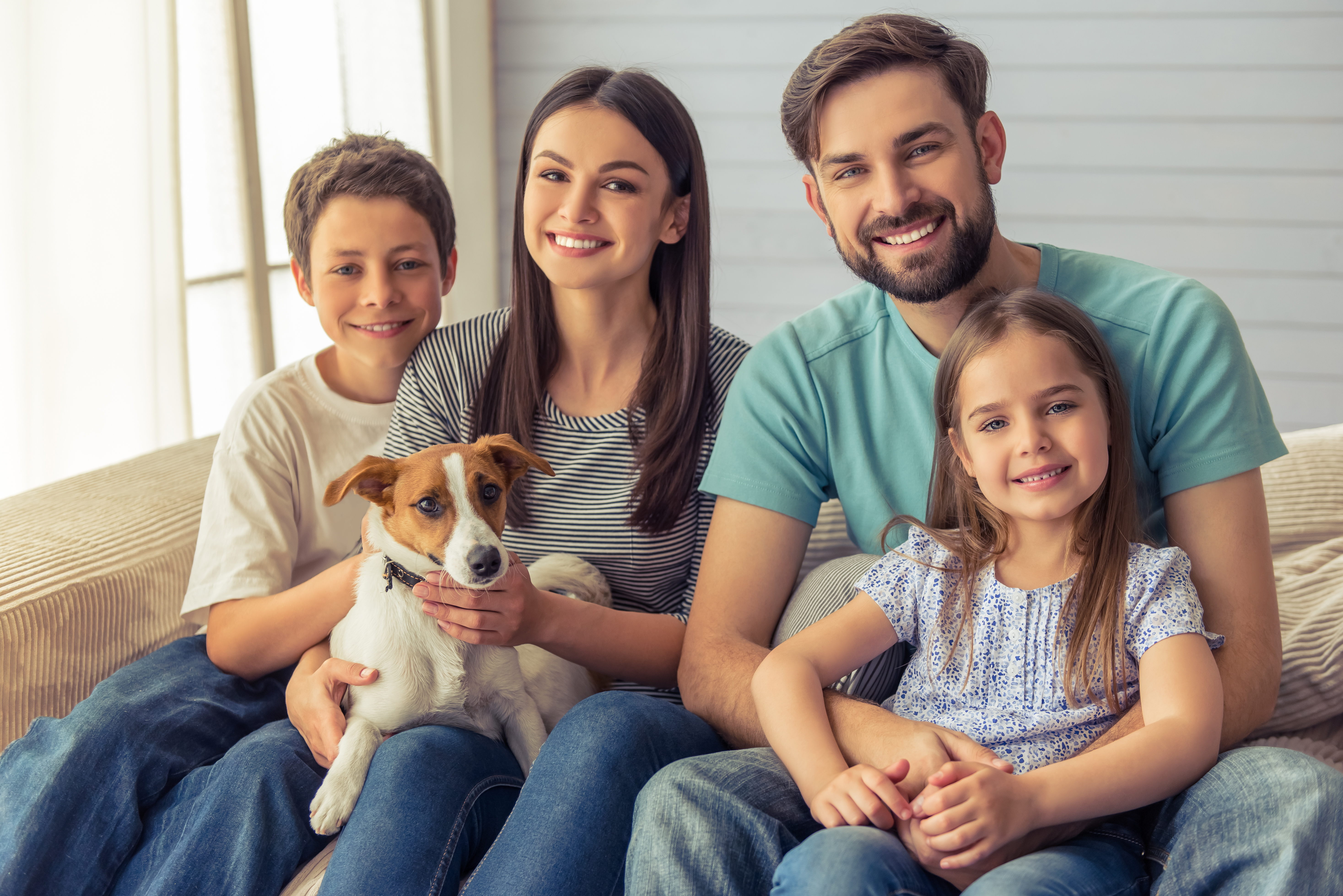 smiling family with dog sitting on couch
